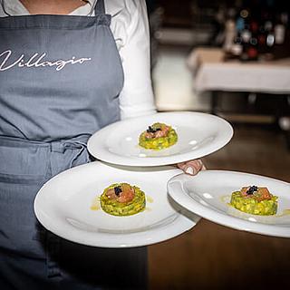 Villagio Kellner hält drei Teller mit leckerem Essen.